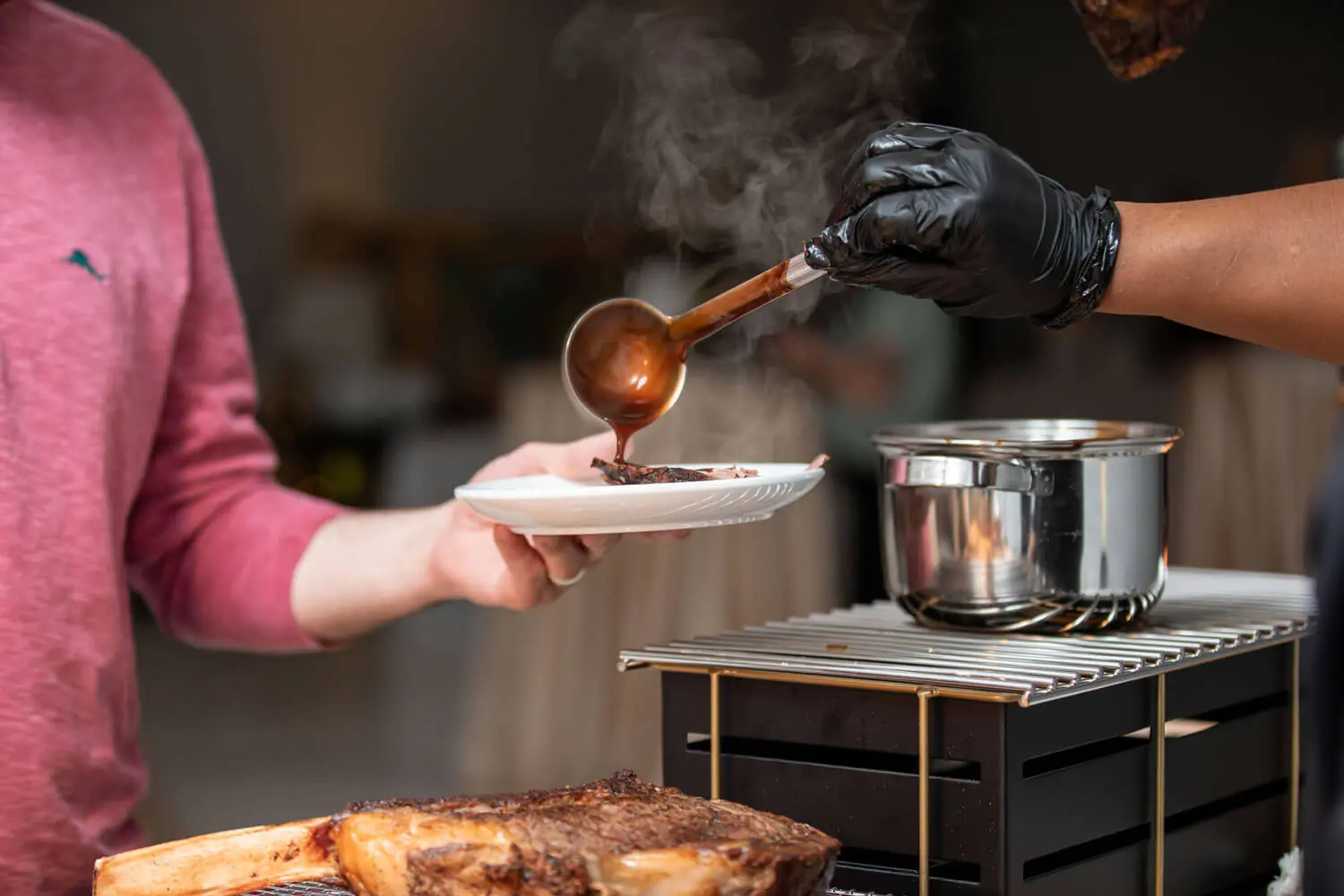 Chef ladling sauce on plate