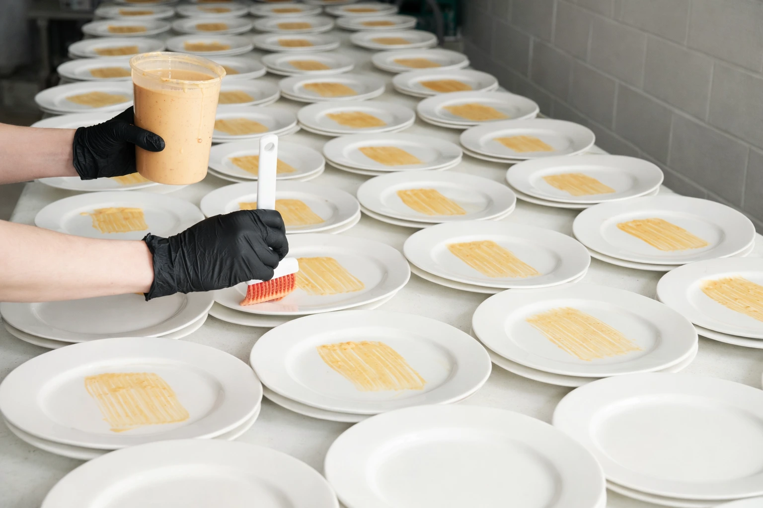 Catering staff carefully plating sauce on dishes during large-scale plated dinner catering service in Baltimore, MD
